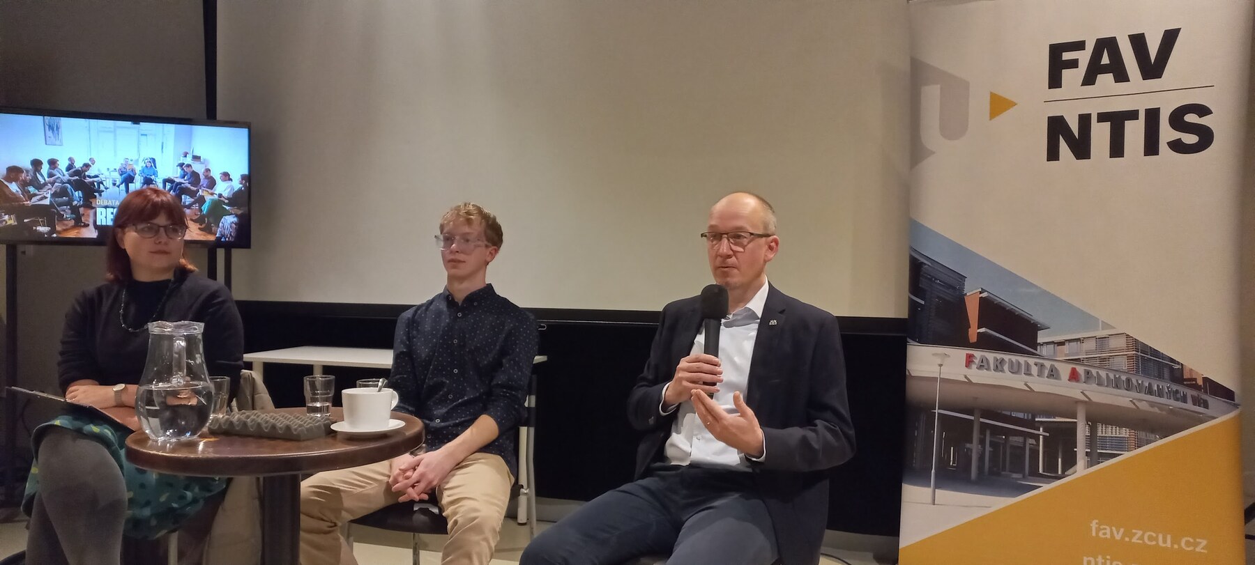 Jan Švec speaking into a handheld microphone during the Debate with Respekt at Moving Station